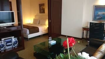 A hotel room with a bed, a TV, a coffee table, a sofa, and a desk with a chair.