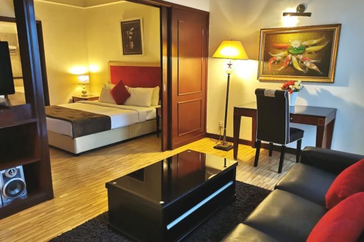 A hotel room with a bed, a desk, a chair, a sofa, and a television.