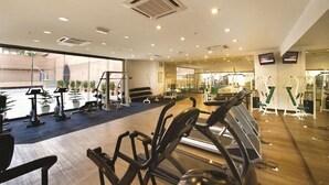 Ein Fitnessraum mit Trainingsgeräten, einem großen Fenster und einem Spiegel.