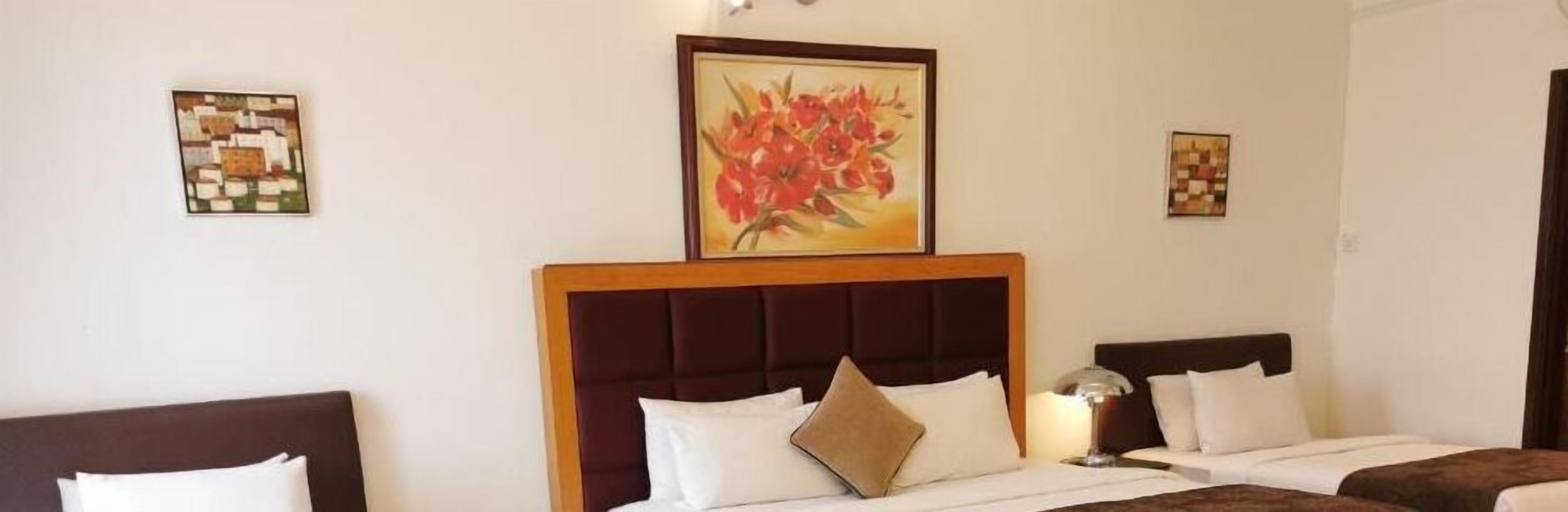 A hotel room with a large bed, two bedside tables, and a painting on the wall.