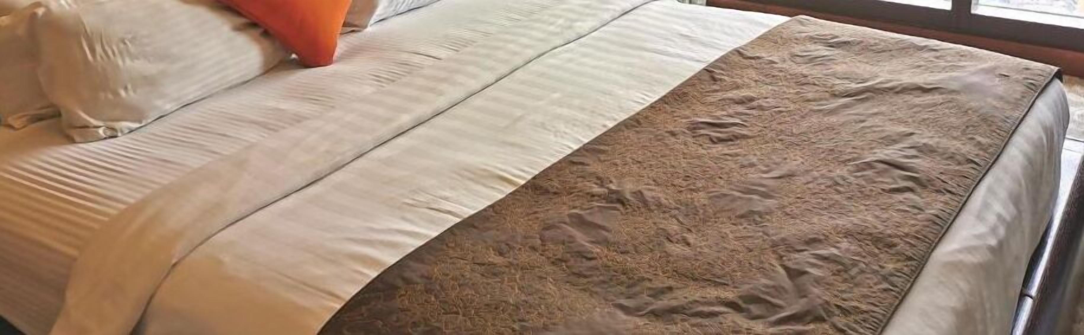 Una cama con una colcha y almohadas estampadas.