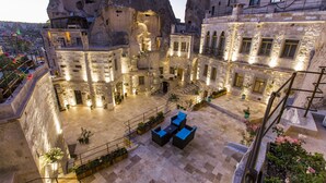 A courtyard with stone walls, outdoor seating, and potted plants.