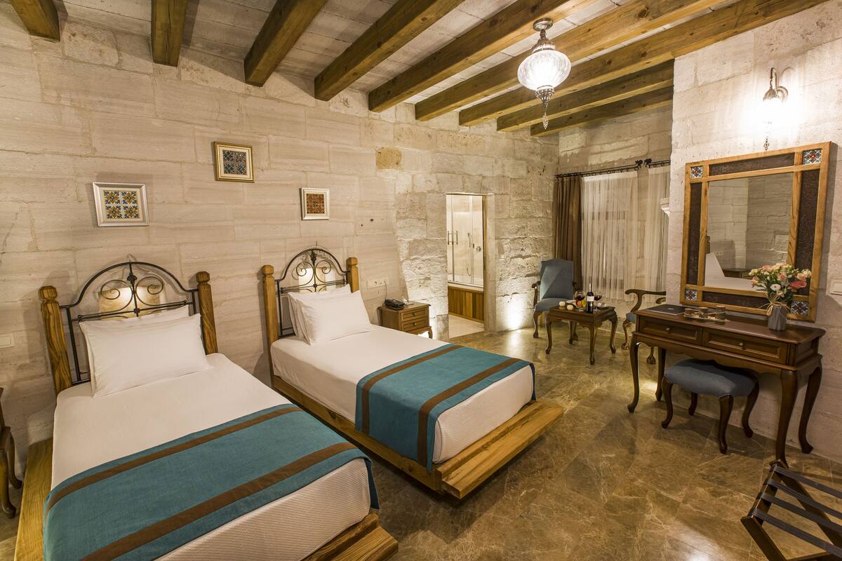 A room with two wooden beds, a desk with a mirror, and a chair.