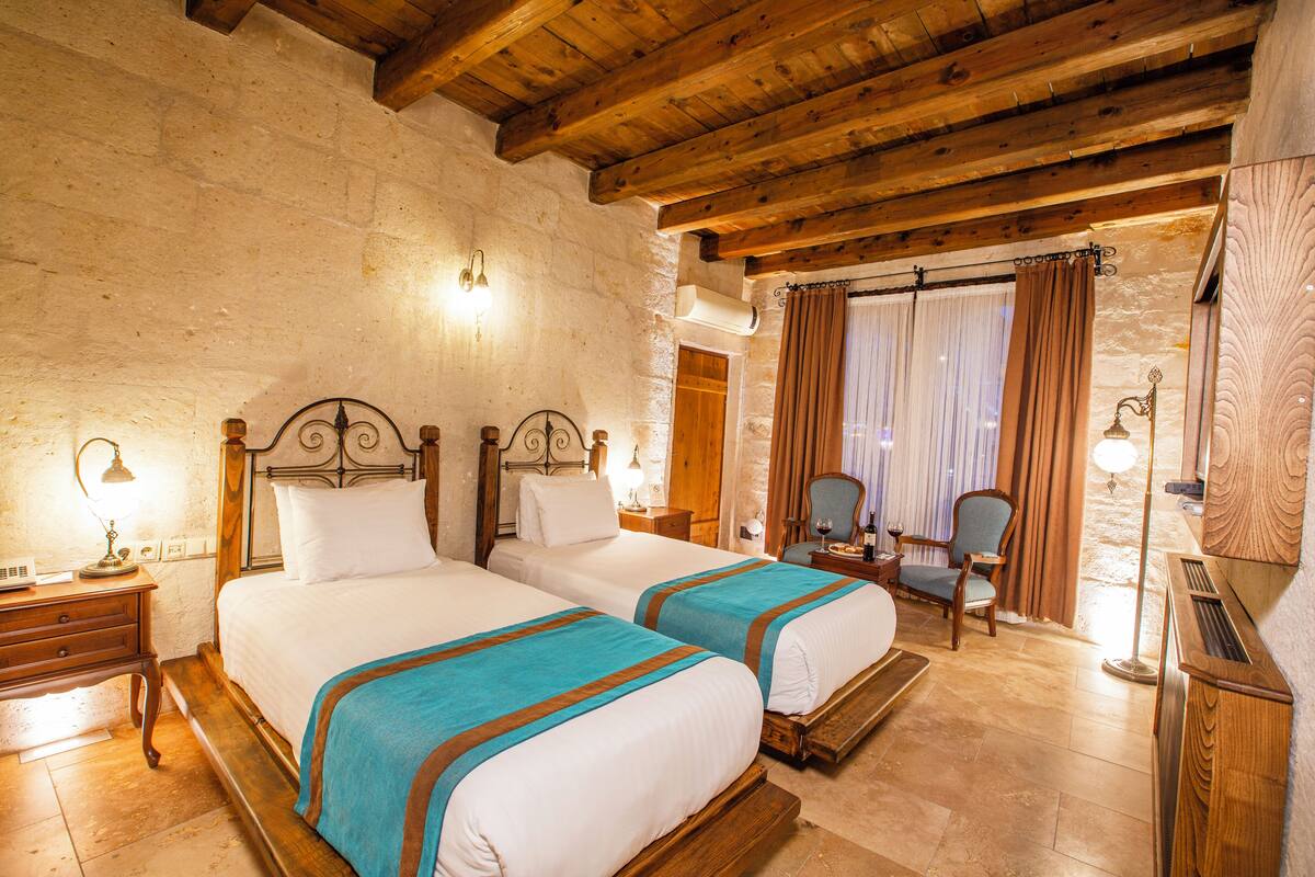 A room with two wooden beds, a wooden chair, a small table, and a mirror.