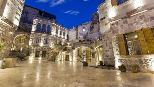 A historic courtyard with stone buildings, arched doorways, and potted plants.