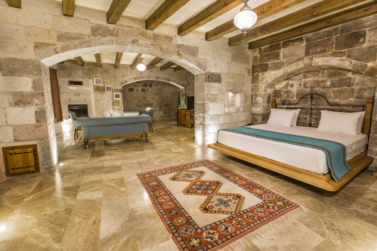 A bedroom with a large bed, a bathtub, and stone walls.