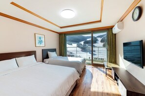 A hotel room with two beds, a large window with a view of a lake, a flat-screen TV, and a wooden ceiling.