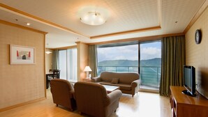 Un salón amplio con un ventanal que ofrece vistas a las montañas, un televisor de pantalla plana sobre un soporte de madera y una zona de comedor con mesa y sillas.