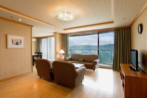 A spacious living room with a large window offering a view of the mountains, a flat-screen TV on a wooden stand, and a dining area with a table and chairs.