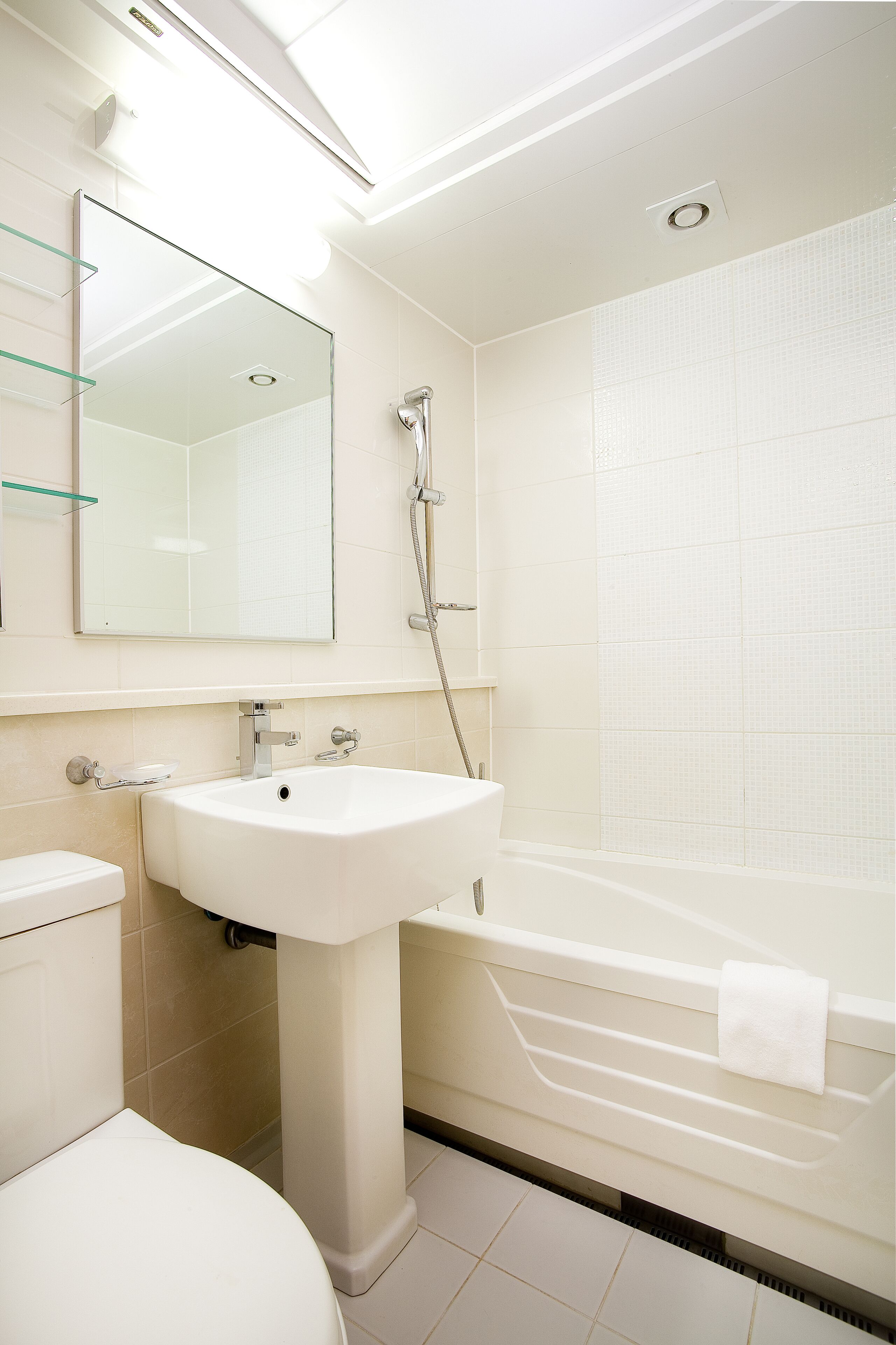 Un baño moderno con lavamanos, espejo y ducha blancos.