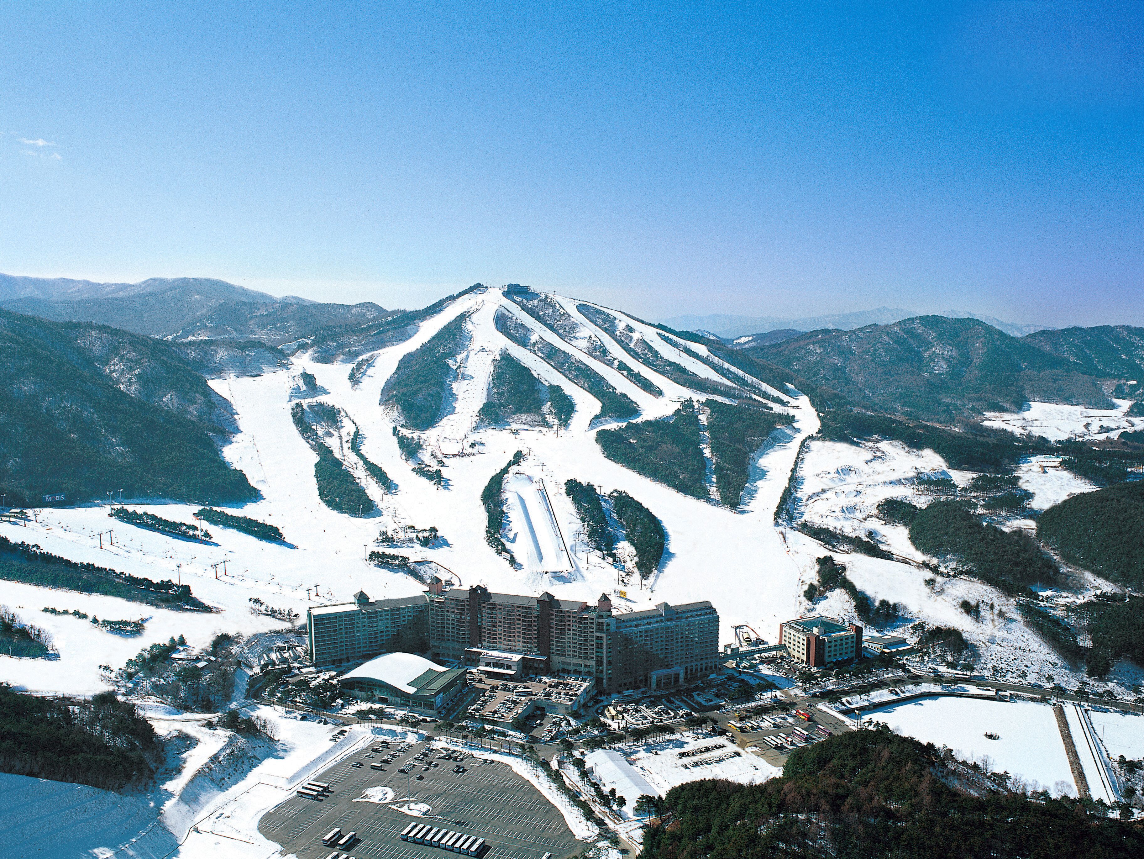 A ski resort with a large building complex, ski slopes, and parking areas.