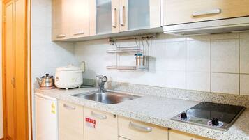 Een moderne keuken met lichte houtkleurige kastjes, een roestvrijstalen spoelbak en een inbouwfornuis.