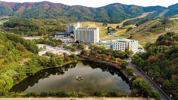 A hotel complex with multiple buildings, a parking area, and a lake with a bridge.