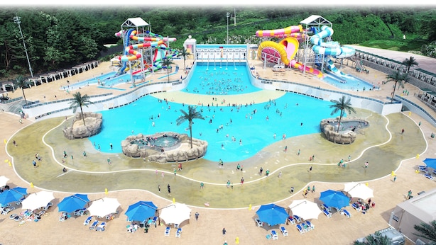 Parque acuático con una amplia piscina central, varias toboganes de agua y tumbonas alrededor de la zona de la piscina.