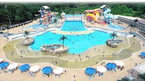 A water park with a large central pool, multiple water slides, and sun loungers around the pool area.