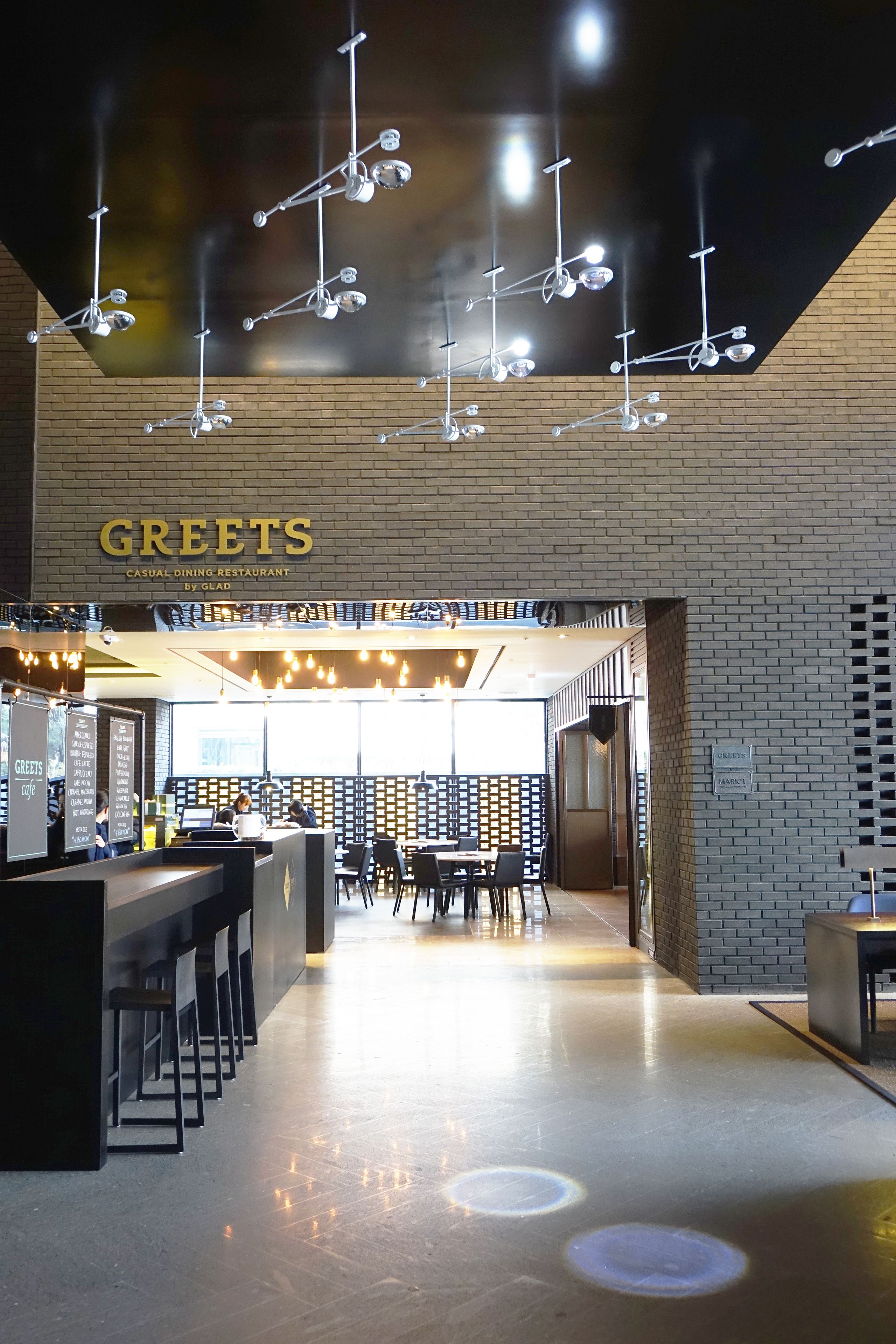 A modern restaurant interior with a bar area, seating, and a visible menu board.