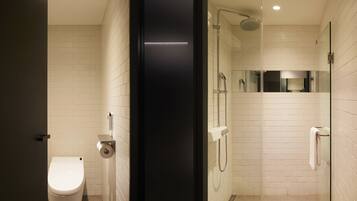 A modern bathroom with a toilet, a glass-enclosed shower, and a mirror.