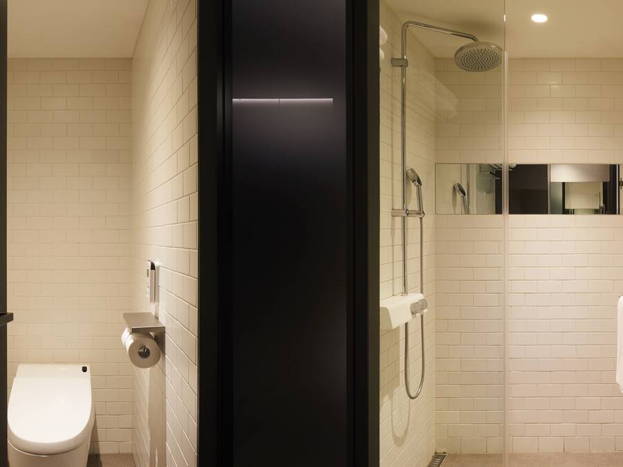 A modern bathroom with a toilet, a glass-enclosed shower, and a mirror.