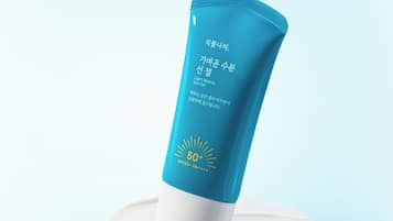 A blue sunscreen tube with SPF 50+ on a white surface.