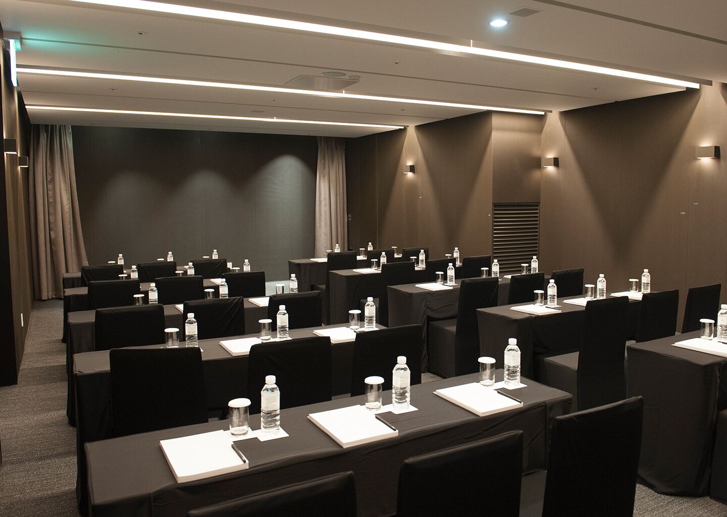 A conference room with multiple tables, chairs, water bottles, and nameplates.