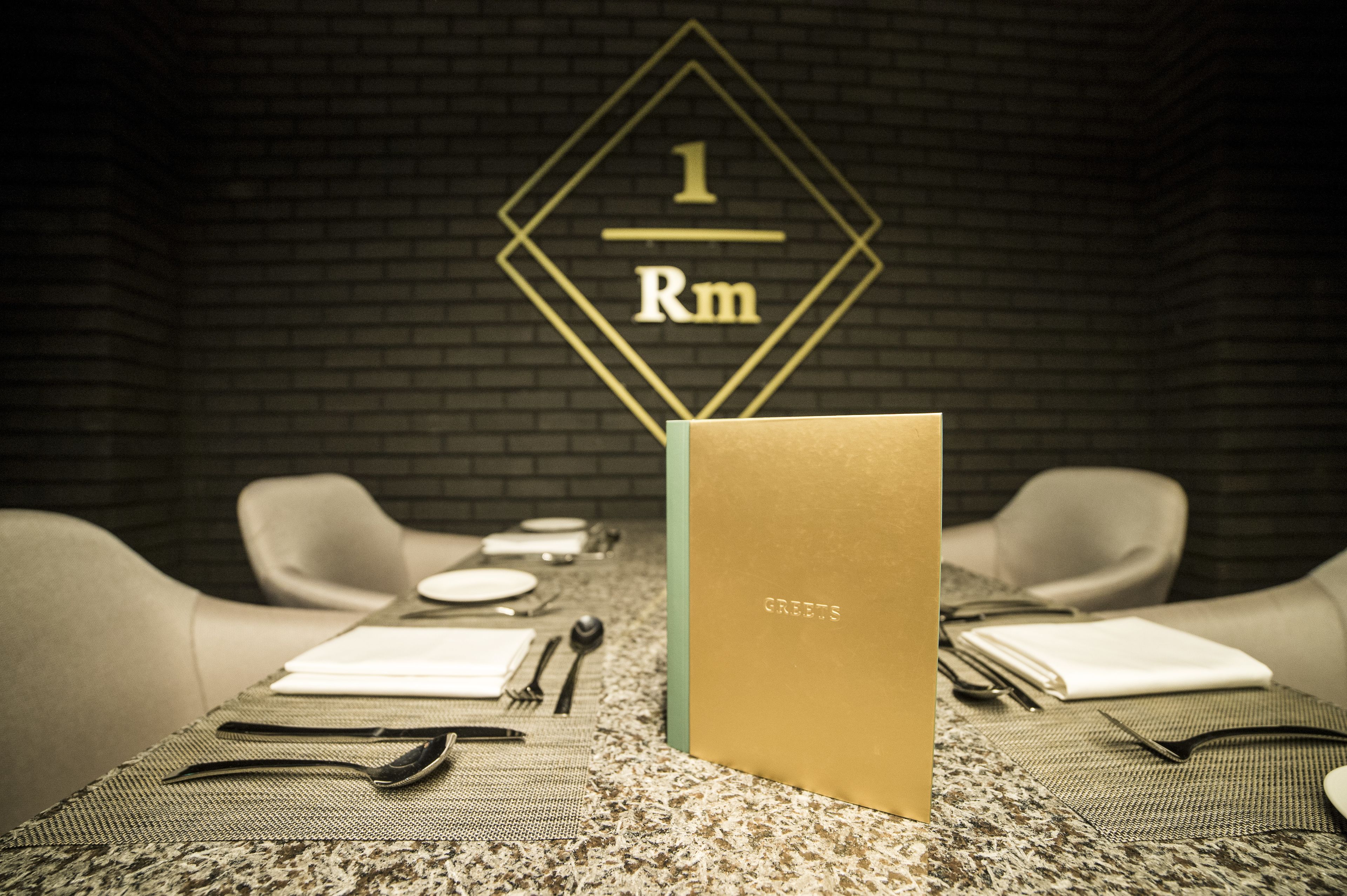 A dining table with a gold card, a notebook, and cutlery.