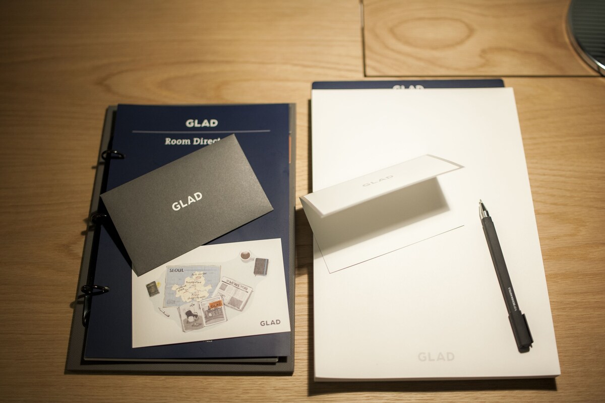 Un classeur GLAD Room Director, un stylo noir et une boîte blanche sur une surface en bois.
