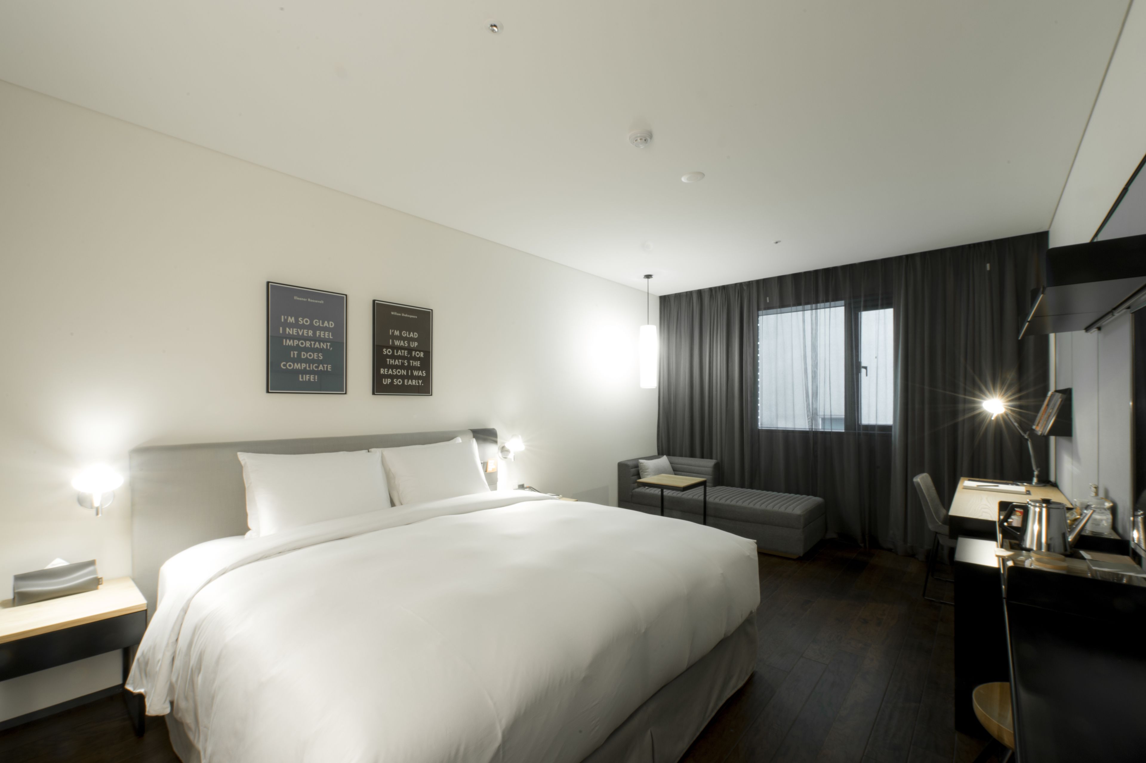 Une chambre d’hôtel moderne avec un grand lit, des tables de chevet, un bureau et une chaise.