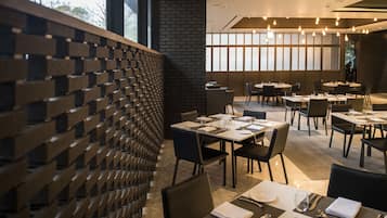 A modern restaurant with brick walls, multiple tables, and chairs.