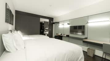 A modern hotel room with a large bed, a bedside table, a mirror, and a TV.