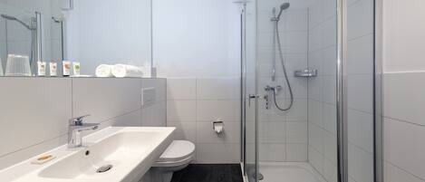 A modern bathroom with a white sink, toilet, and glass-enclosed shower.