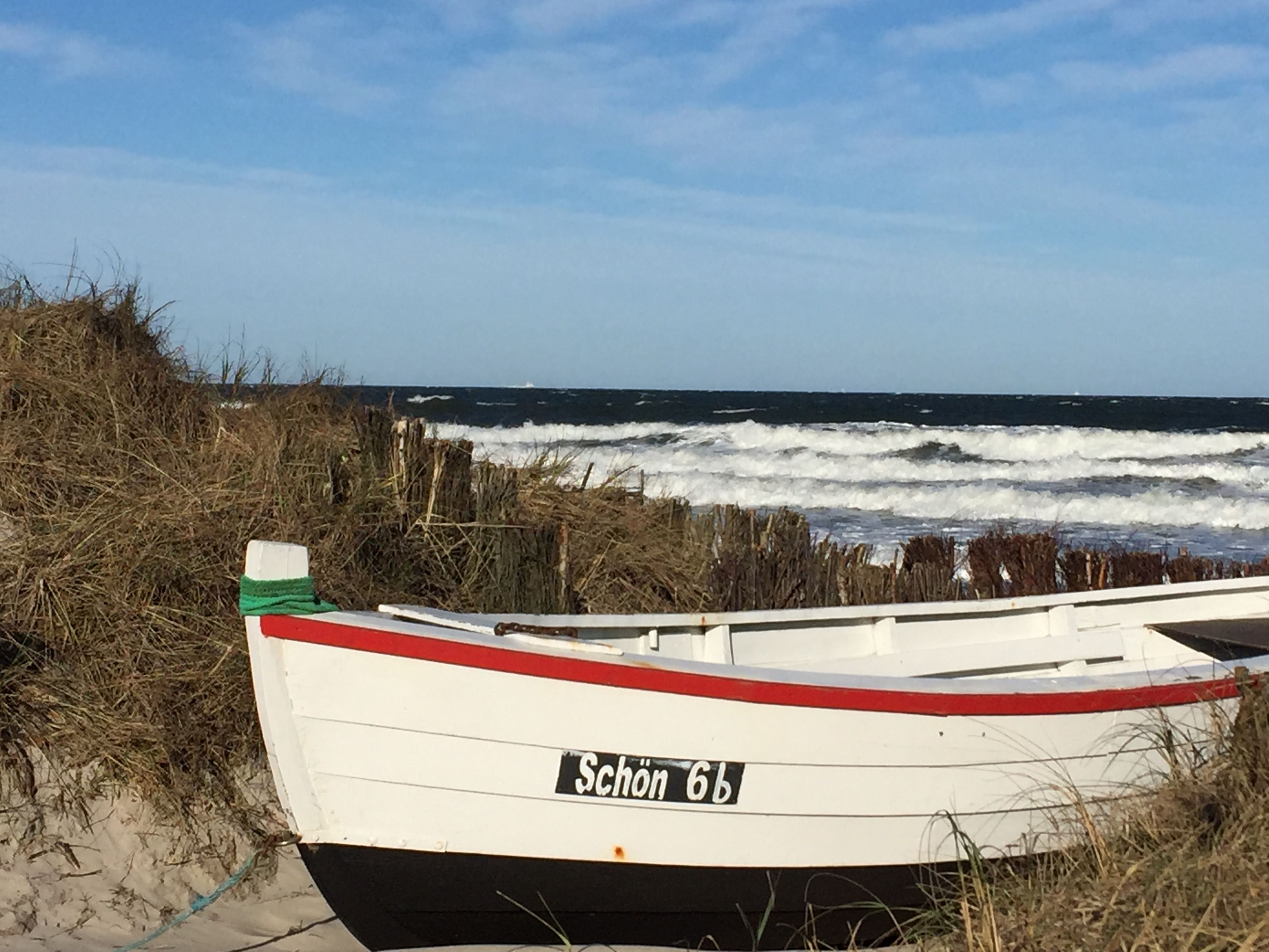 Un bateau baptisé « Schön 66 » était amarré près d’une plage, avec des vagues en arrière-plan.