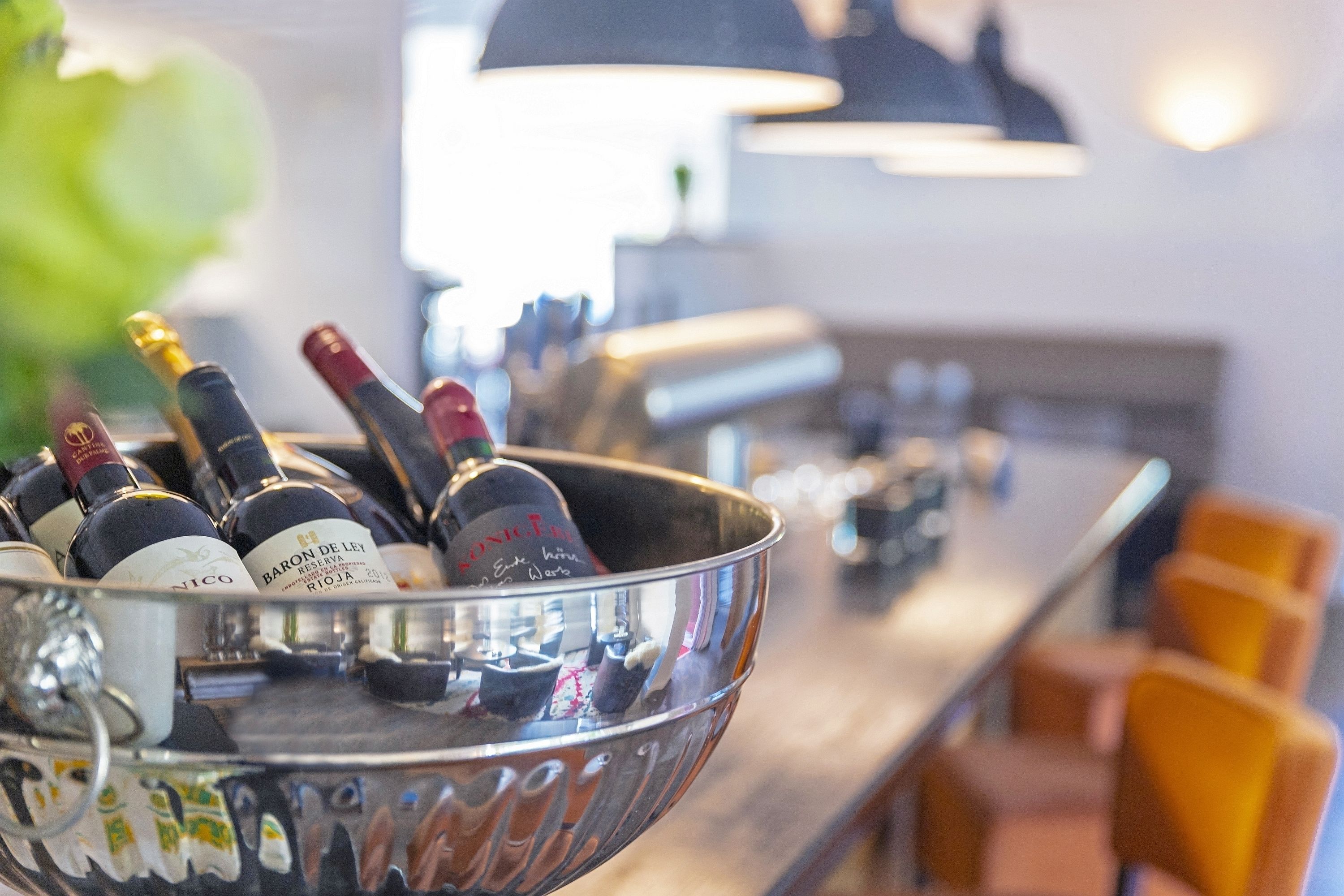 A bar area with a metal bowl containing several bottles of wine.