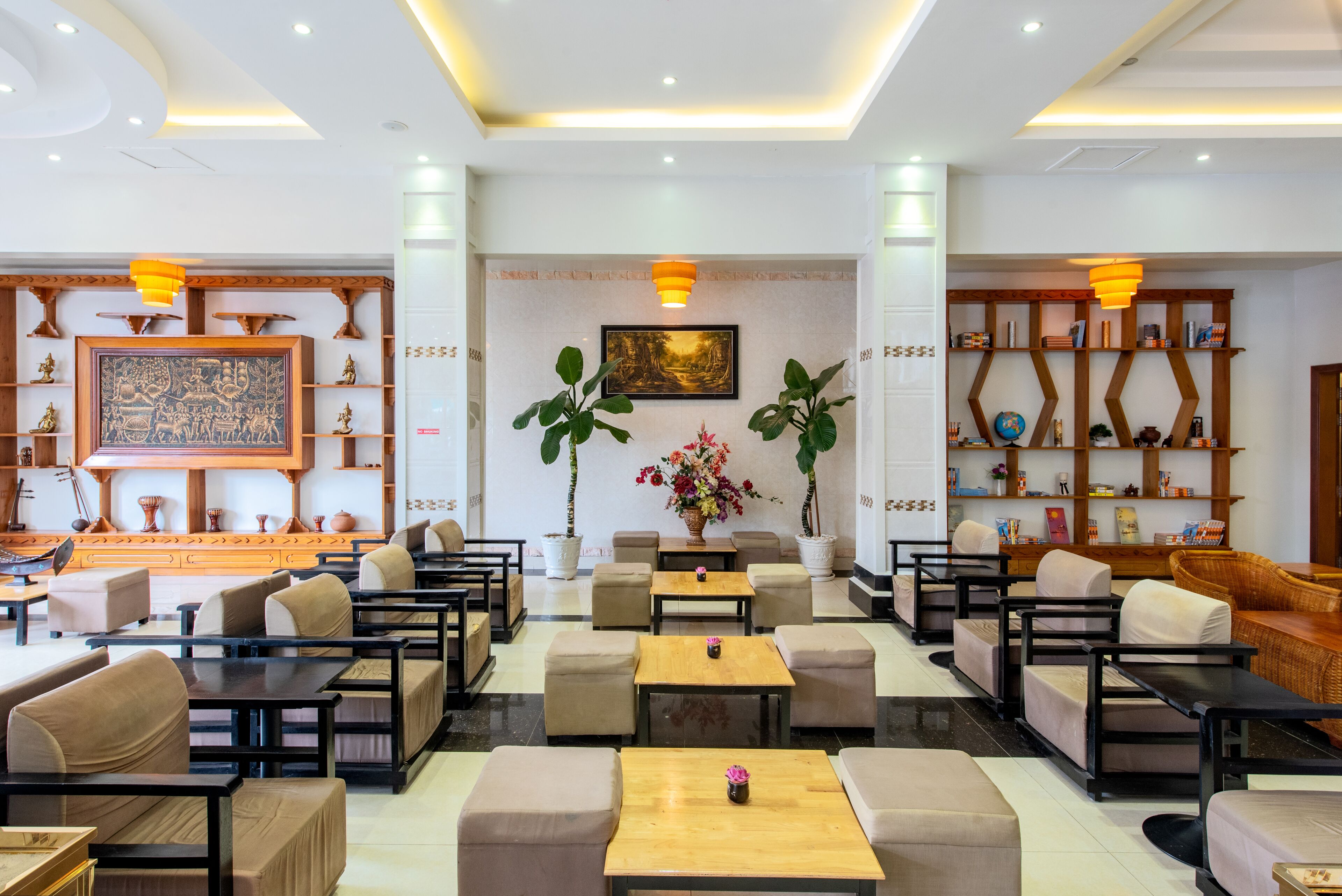 A spacious lobby with multiple seating areas, a central floral arrangement, and a large framed artwork on the wall.