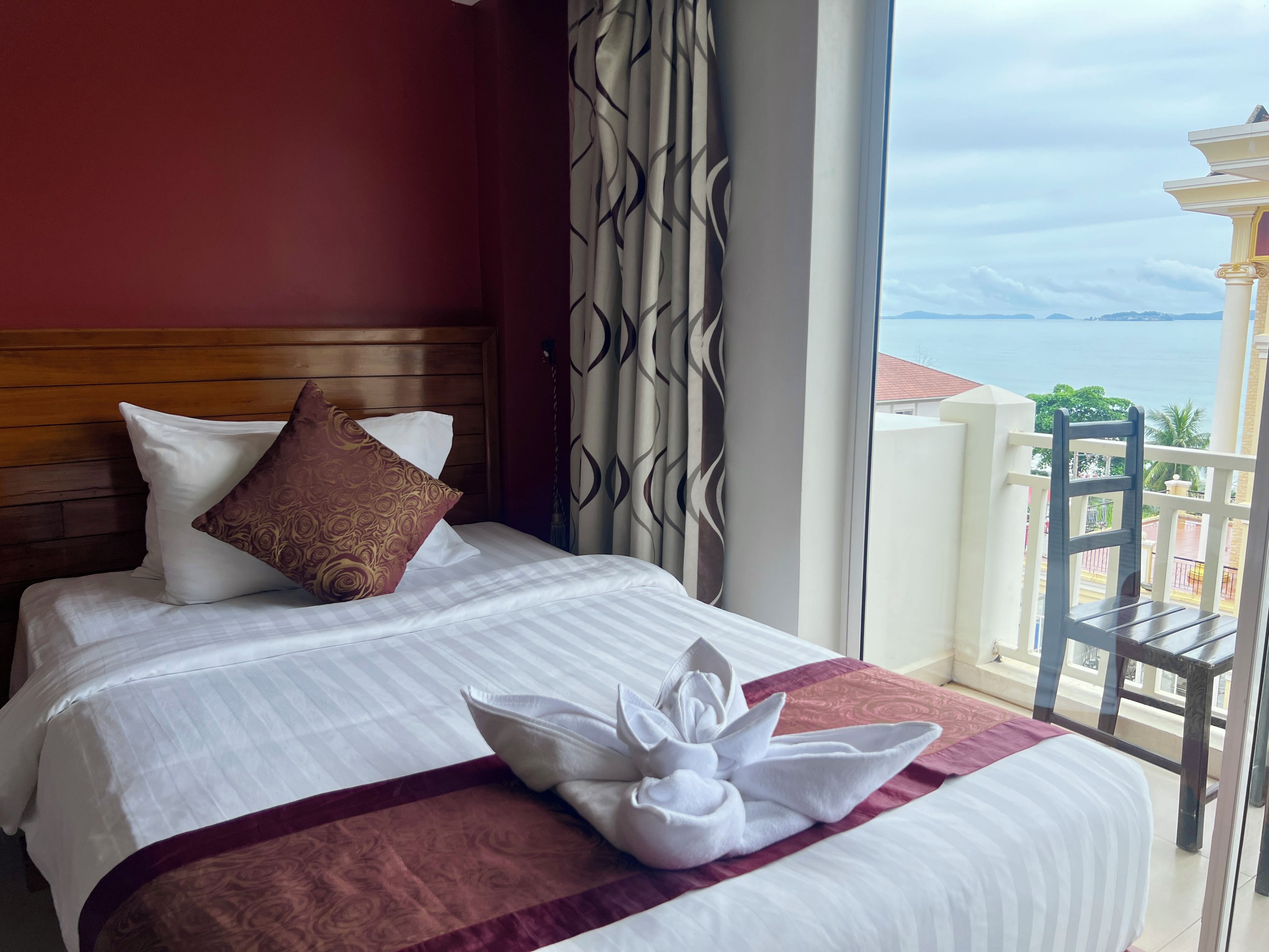 Habitación de hotel con cama, almohadas, toalla y vista al mar.