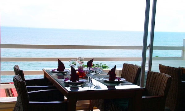 Une table à manger dressée pour deux personnes, avec vue sur l’océan.