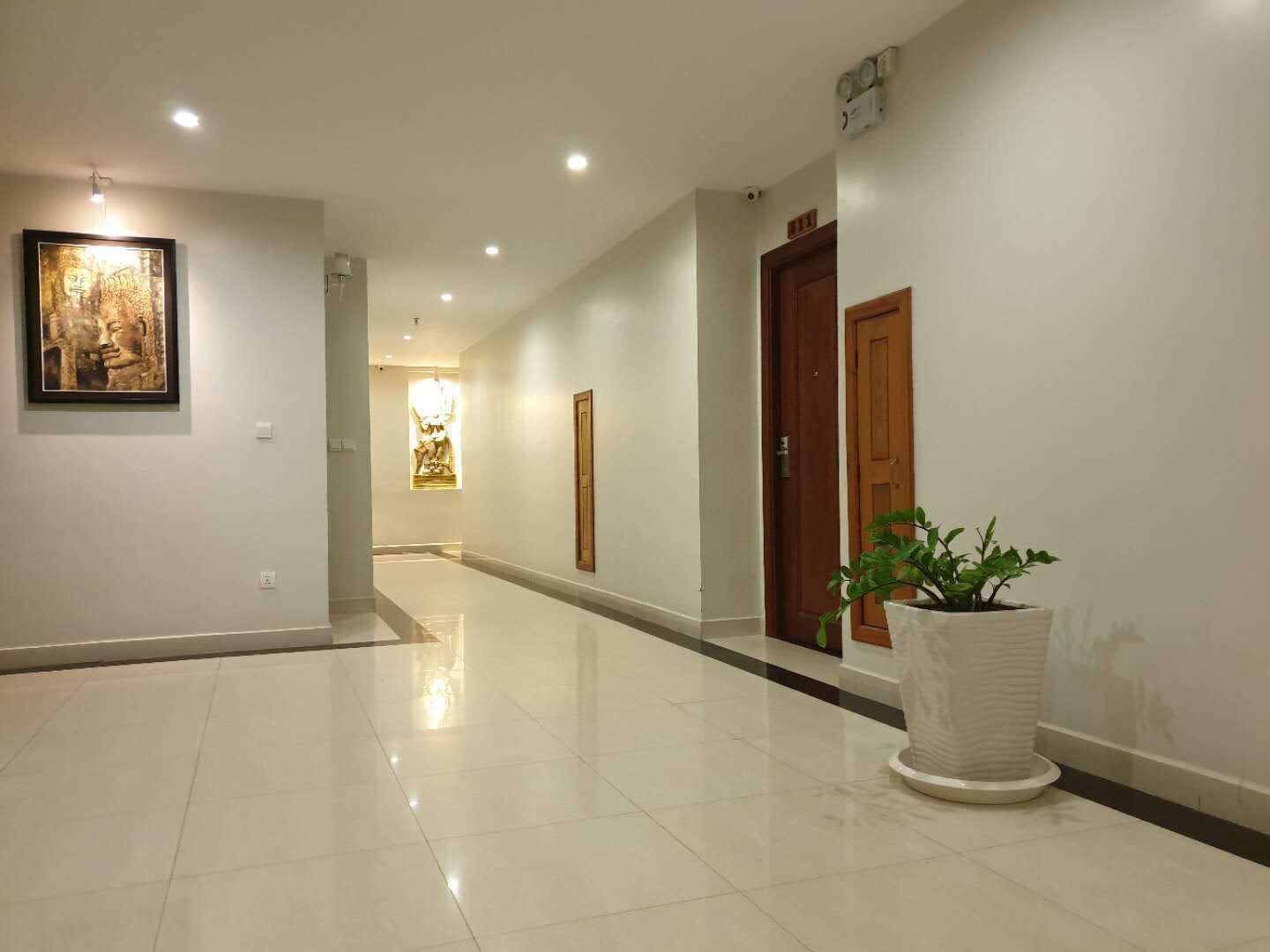A clean, well-lit hallway with tiled floors, a potted plant, and artwork on the walls.