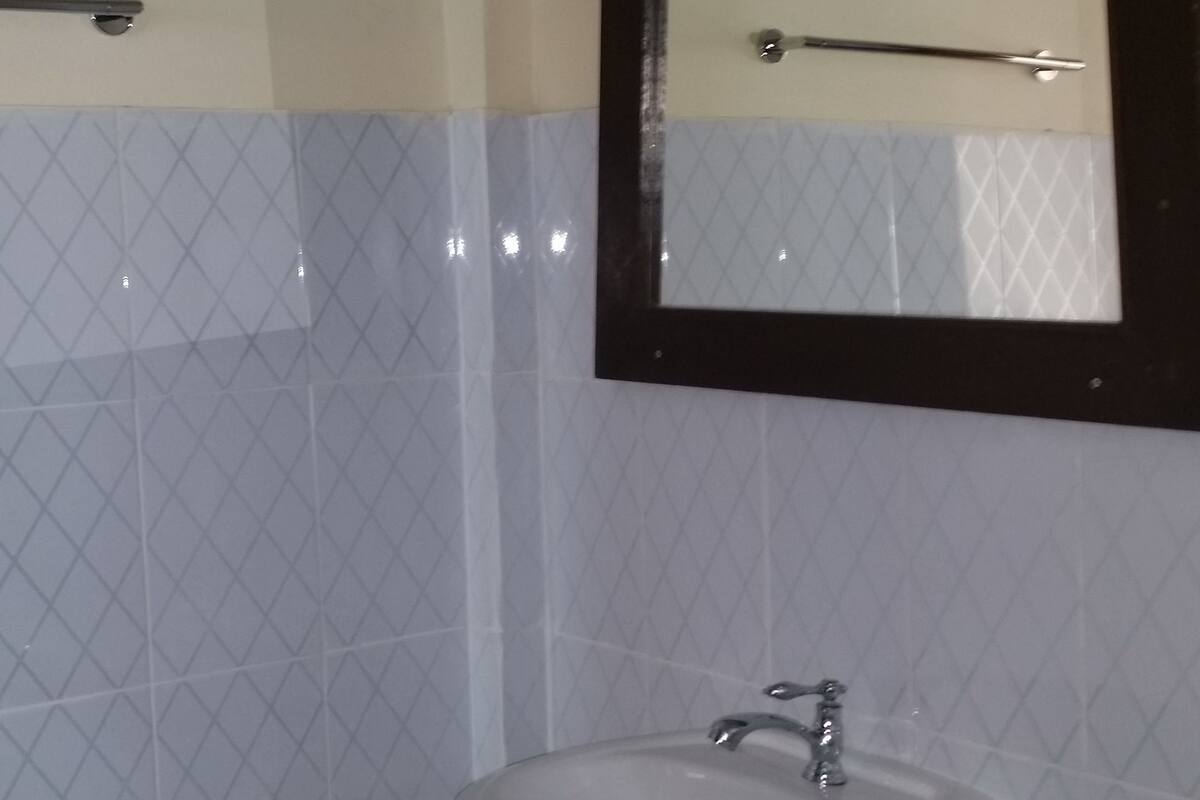 Une salle de bain équipée d’un lavabo, d’un miroir et d’un porte-serviettes.