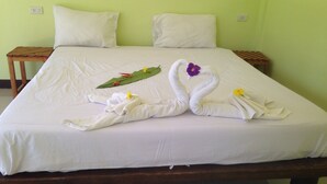 Cama com lençóis brancos e arranjo decorativo de toalhas.