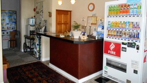 A reception area with a counter, a fire extinguisher, a clock, and a vending machine. - Gamagori Orange Pension (Gamagori)