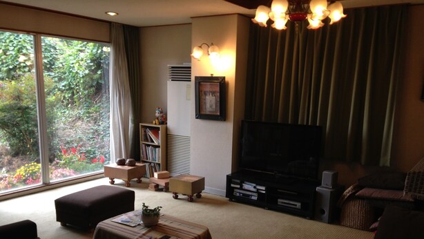 A living room with a large window, a flat-screen TV, a bookshelf, and a sofa. - Gamagori Orange Pension (Gamagori)