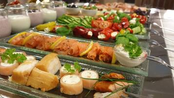 Un bufé con diferentes opciones de comida, incluyendo salmón ahumado, vegetales y salsas.