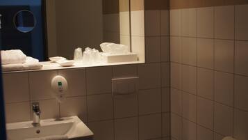 Une salle de bain équipée d’un lavabo, d’un miroir, de toilettes et d’un porte-serviettes.