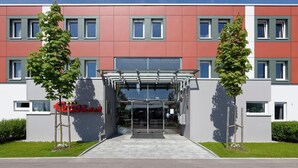 A modern hotel entrance with a glass facade, a covered entrance area, and a sign indicating the hotel name. - Euro Hotel Friedberg (Friedberg)