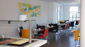Un comedor moderno con un bufé, varias mesas y sillas.