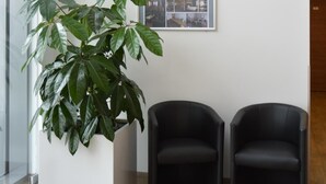 A reception area with a potted plant, two black chairs, and a framed welcome poster on the wall. - Euro Hotel Friedberg (Friedberg)