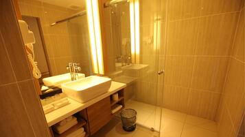 A bathroom with a sink, mirror, shower, and toilet.