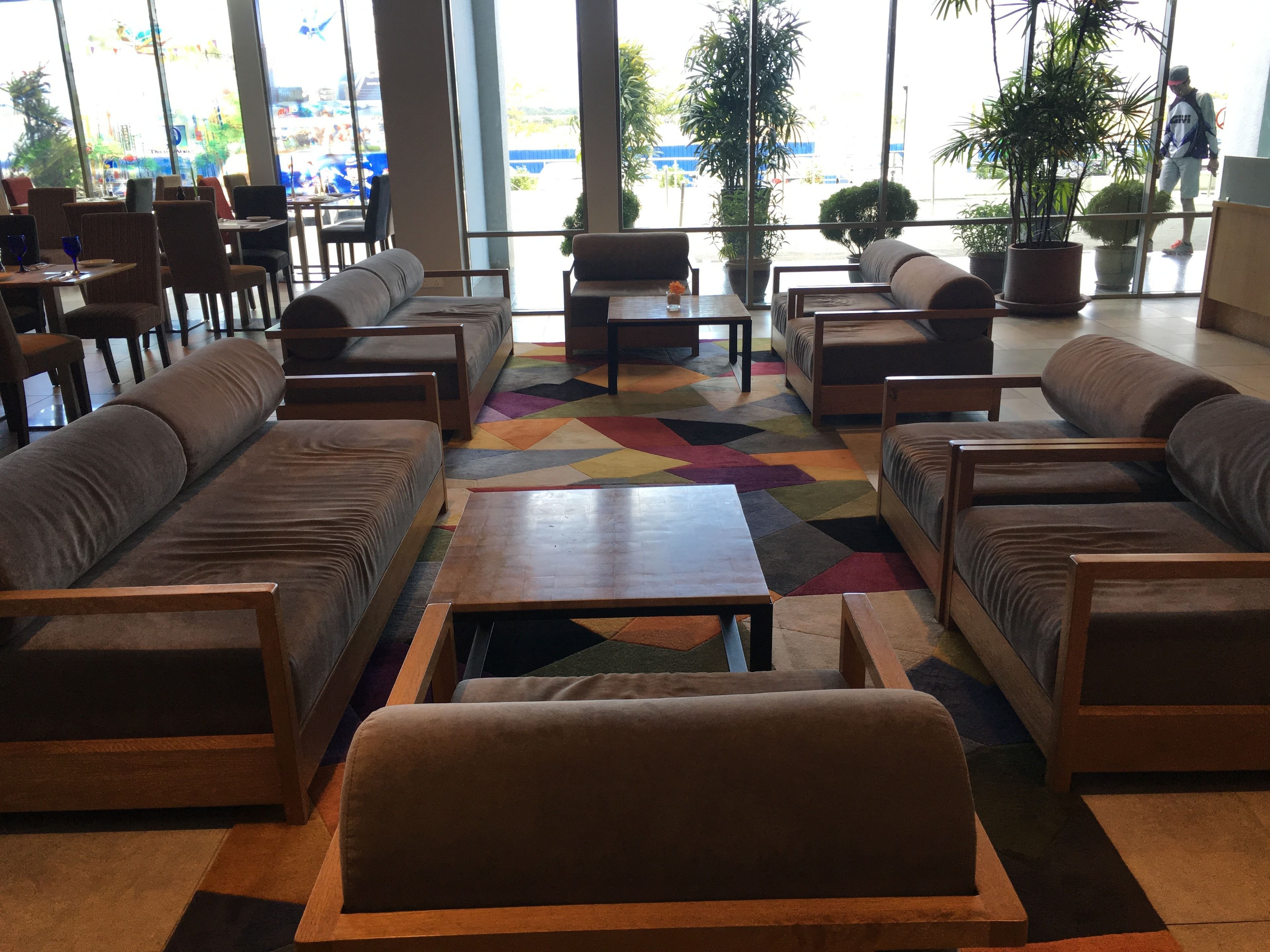 A spacious indoor seating area with sofas and tables, large windows offering a view of the outside.