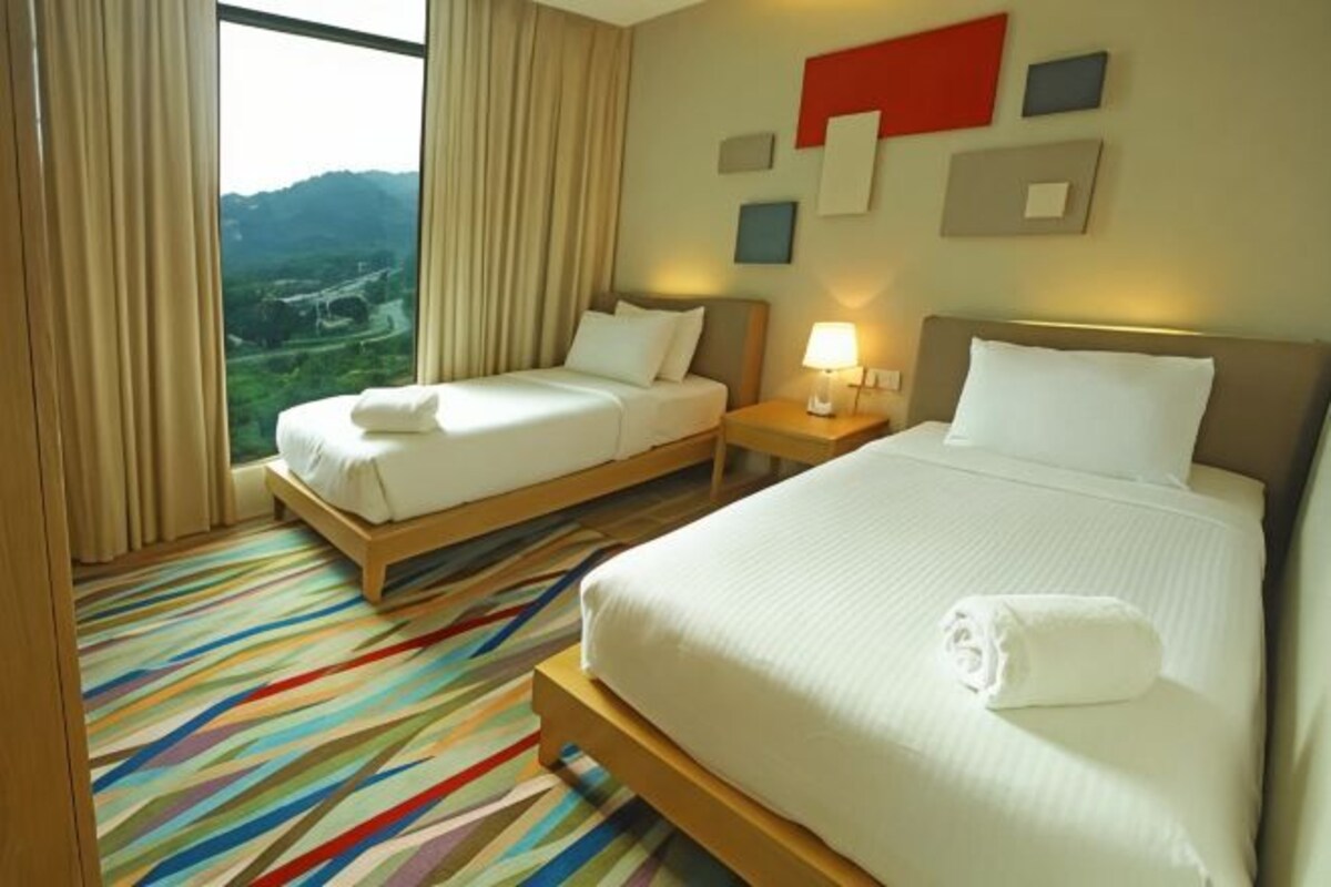 A hotel room with two beds, a view of the outdoors, and a striped carpet.