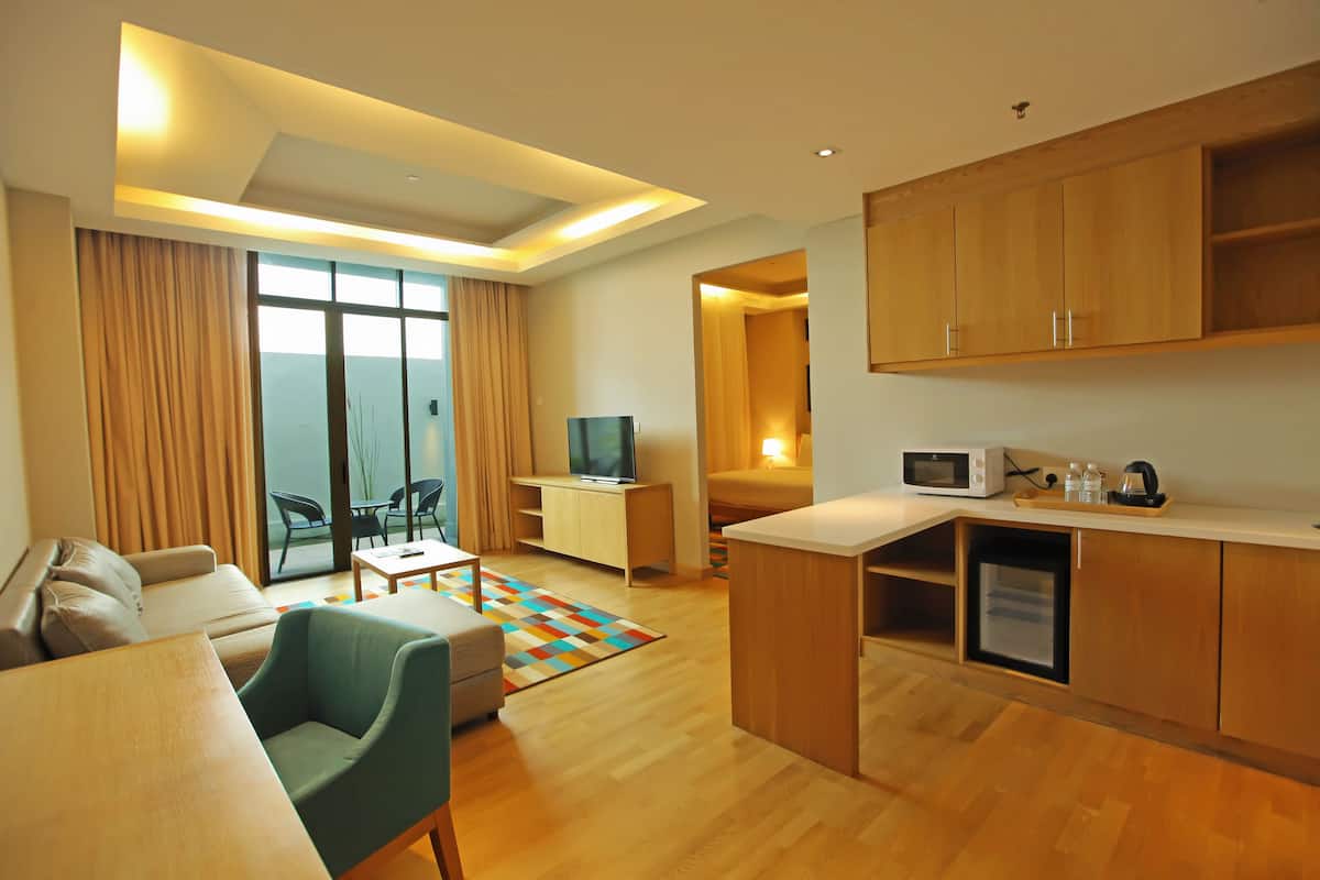 Habitación de hotel moderna con sofá, una mesita, televisor, kitchenette y vistas al mar.