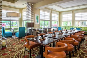 A restaurant with multiple dining tables, chairs, and a patterned carpet. - Hilton Garden Inn Bettendorf/ Quad Cities (Bettendorf)